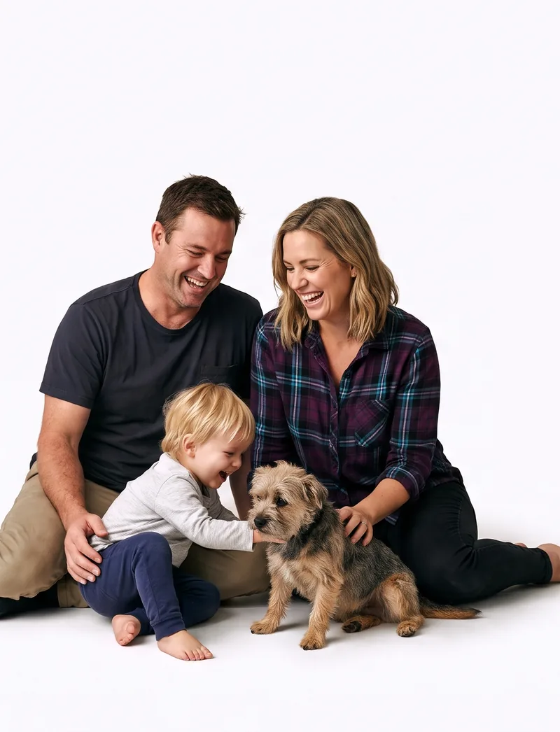 A couple laughing with their toddler and dog